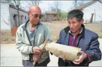  ??  ?? Left: Wang Junmin (right) and Yang Zhixi, two farmers from Liangwudi village, Chunhua county, Shaanxi province, display a Qin brick in the village on April 14. Right: Ren Baojun, a photograph­er from Chunhua, points to the ruins of the roadbed of the Qinzhidao in Liangwudi village, the starting point of the road, on April 14.