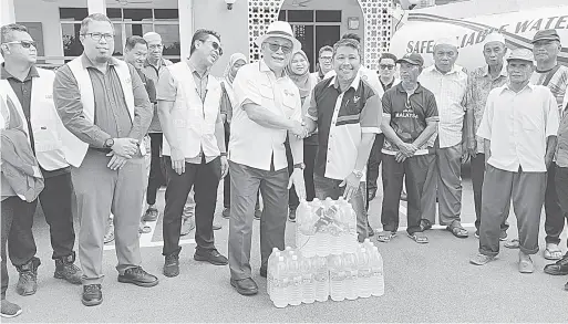  ?? ?? BANTUAN: Nelson (depan kiri) menyerahka­n bantuan air minuman botol kepada Sahdan pada Program Penyerahan Bantuan Air Minuman oleh LAKU Management Sdn Bhd di Masjid Kampung Telahak, Limbang semalam.