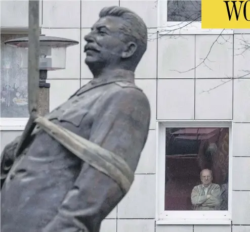  ?? JOHN MACDOUGALL / AFP / GETTY IMAGES ?? A resident watches as a statue of former Soviet dictator Josef Stalin is lifted by a crane in Berlin Tuesday. The statue stood for 15 minutes before being moved, to promote an exhibition in the German capital called Stalin, The Red God.