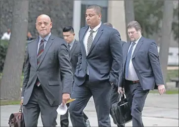  ?? Gary Coronado Los Angeles Times ?? JONATHAN MARTIN, center, walks with his attorney Winston McKesson, left, to be booked at LAPD.