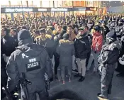  ??  ?? German police keep a watch on a group of migrant men. Feelings still run high over Germany’s open-door policy