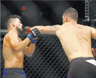  ?? Steve Luciano ?? The Associated Press Former UFC middleweig­ht champion Chris Weidman lands a left to the chin of Kelvin Gastelum during their bout at UFC onFox 25 on Saturday in Uniondale, N.Y. Weidman halted a three-match losing streak by winning with a third-round submission.