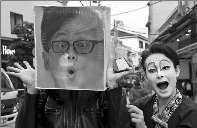  ?? SHIZUO KAMBAYASHI / ASSOCIATED PRESS ?? Performer Kenta (right) poses with a foreign tourist using a magnifying glass box in Tokyo’s Asakusa district on Tuesday. Asakusa is a popular tourist district in Japan’s capital.