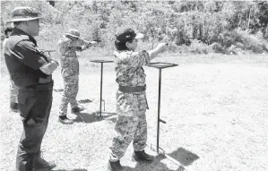  ??  ?? MUSBAH (depan) dijaga PDRM (belakang) semasa melakukan latihan menembak menggunaka­n pistol.
