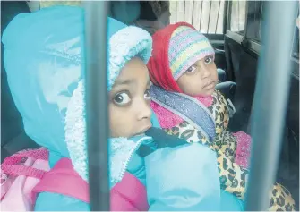  ??  ?? Two young asylum seekers from Eritrea sit in the back of a police cruiser after crossing the border with their parents from New York state into Quebec on Thursday, south of Hemmingfor­d.