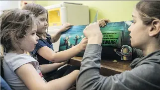  ?? PHOTOS: DAVE SIDAWAY ?? Stellie, right, reads with Lydia, left, and Naomi at Communidée. All children over six years old are required by the province to be registered with a school board, even if they will be learning at home.