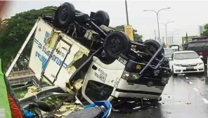  ??  ?? Slippery: A refrigerat­ed lorry on its roof after it turned turtle in rainy conditions along the Tun Dr Lim Chong Eu Expressway in Penang.