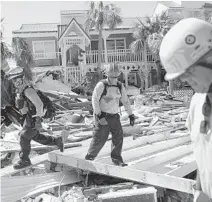  ?? JOE RAEDLE/GETTY ?? Members of the South Florida Urban Search and Rescue team look for survivors after Hurricane Michael passed through Mexico Beach.