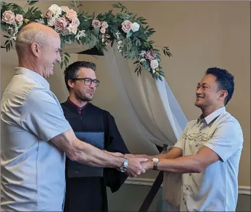  ?? PHOTOS BY JAKE HUTCHISON — ENTERPRISE-RECORD ?? Christophe­r Hest, left, joins hands with Louie Abid during a wedding ceremony officiated by Butte County Clerk-Recorder Keaton Denlay, center, on Tuesday in Oroville.
