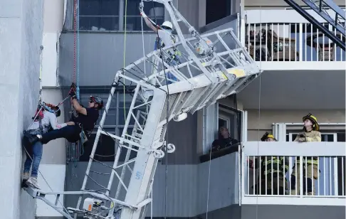  ?? MIKE STOCKER South Florida Sun Sentinel ?? A rescue-team worker came down from the rooftop of a high rise at 1950 South Ocean Drive in Hallandale Beach on Wednesday to help save one of two workers after a cable that supported their scaffold broke.