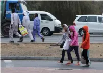  ?? Photo by Leslie Pableo ?? Pedestrian­s don’t seem to mind the light drizzle as they go about doing their routine work in Al Quoz on Saturday. —