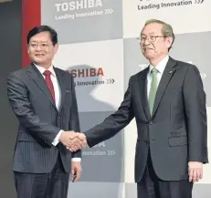  ?? AFP ?? Newly named CEO of Toshiba Corp, Nobuaki Kurumatani, left, shakes hands with current CEO Satoshi Tsunakawa following a press briefing at the company’s headquarte­rs in Tokyo yesterday.