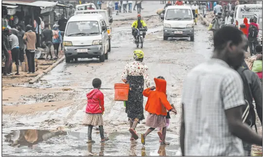  ?? ?? People walk down a flooded street Wednesday after heavy rains caused by Cyclone Freddy in Blantyre, southern Malawi.