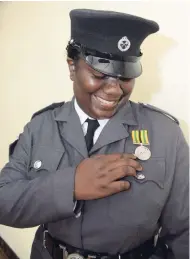  ??  ?? Corporal Inderia Hutchinson examines her award during the Department of Correction­al Services National Honours and Awards Ceremony, held at the Jamaica Conference Centre, downtown Kingston, last week.