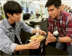  ?? — Photos: YAP CHEE HONG/The Star ?? Look ma, no hands – Chan (left) showing off the ‘floating light bulb’ to a potential customer.