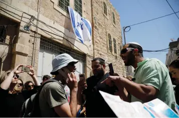  ?? (Amir Cohen/Reuters) ?? SETTLERS ARGUE with Nadav Weiman (left), the educationa­l director of Breaking the Silence, as he leads visitors on a tour in Hebron in April.