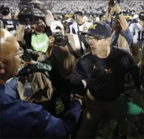  ?? CHRIS KNIGHT — THE ASSOCIATED PRESS ?? Michigan coach Jim Harbaugh, right, shakes hands with Penn State coach James Franklin on Oct. 21 in State College, Pa. Penn State won 42-13.