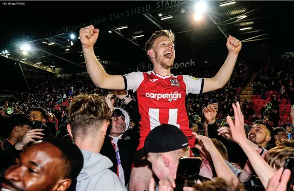  ?? Phil Mingo/PPAUK ?? > Exeter City captain Matt Jay is lifted and celebrates promotion to League One with the supporters after the victory against Barrow at St James Park