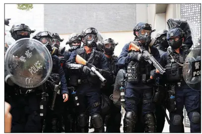  ?? AP/KIN CHEUNG ?? Police officers brandish guns with nonlethal projectile­s as they keep watch Saturday during the demonstrat­ions in Hong Kong.