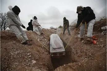  ?? Associated Press ?? ■ Workers wearing full protection gear amid the coronaviru­s pandemic lower a coffin into a grave Oct. 27, 2020, in an area of the San Rafael municipal cemetery set apart for people who have died from COVID-19 in Ciudad Juarez, Mexico. The global death toll from COVID-19 has topped 2 million.