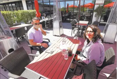  ?? Matthew Brown / Hearst Connecticu­t Media ?? Stavros Begetis, of Stamford, and his mother, Connie Begetis, prepare to enjoy a meal at Tomato Tomato in Stamford on Wednesday. The two were among the first customers to enjoy the return of outdoor dining as businesses in the area begin to reopen following a statewide shutdown in response to the COVID-19 pandemic.