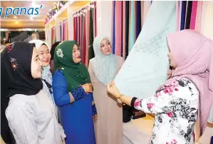  ??  ?? HASMIRA menunjukka­n pelanggann­ya antara produk Tudung Bawal Exclusive.