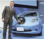  ?? YOSHIKAZU TSUNO, AFP/GETTY IMAGES ?? Nissan CEO Carlos Ghosn charges the Leaf, the most popular EV on the road.