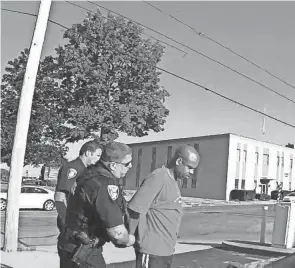  ?? RAVENNA POLICE DEPARTMENT ?? Darren Cooper, right, is detained Aug. 13 in front of the Portage County Job and Family Services building by two Ravenna police officers after a caller falsely reported he had a gun. It was a cellphone.