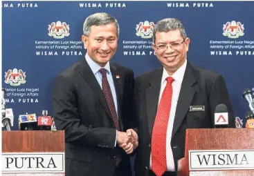  ??  ?? Working together: Saifuddin (right) andDr Vivian shaking hands after a joint press statement in Putrajaya.