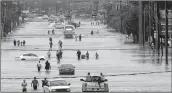  ??  ?? People walk through flooded waters in Houston on Monday.