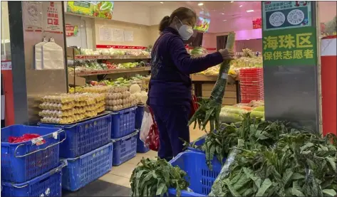  ?? PHOTOS BY THE ASSOCIATED PRESS ?? A woman shops in a reopened grocery store in the district of Haizhu as pandemic restrictio­ns are eased in southern China’s Guangzhou province on Thursday. More Chinese cities eased some anti-virus restrictio­ns as police patrolled their streets to head off protests Thursday while the ruling Communist Party prepared for the high-profile funeral of late leader Jiang Zemin.