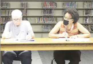  ?? Katie West • Times-Herald ?? Forrest City School Board President Sandra Taylor listens as another board member speaks during the Thursday night board meeting while board Larry Devasier reviews documents. The board agreed last night to begin offering $200 monthly incentives to each staff member who receives the Covid vaccinatio­n.