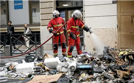  ?? AP ?? Firemen control the remains of a garbage fire from overnight protests against the retirement bill in Paris.