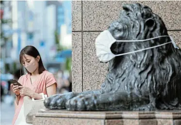  ?? Picture: ANDRONIKI CHRISTODOU­LOU/REUTERS ?? MASK AWARENESS: A woman wearing a protective face mask stands next to a masked lion statue in Ginza shopping area amid the coronaviru­s outbreak in Tokyo, Japan, yesterday