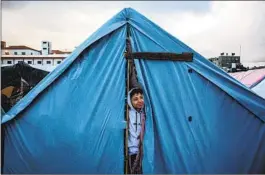  ?? YOUSEF MASOUD NYT ?? A child looks out of a tent in Khan Younis in the southern Gaza Strip, where many displaced Palestinia­ns have sought refuge.