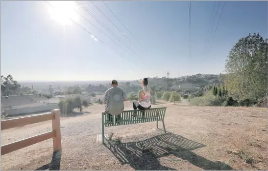  ?? Allen J. Schaben Los Angeles Times ?? STROLLERS take in the view from the high point of Monterey Park’s Edison Trail, a favorite for those looking to work off calories from their dim sum feast below.