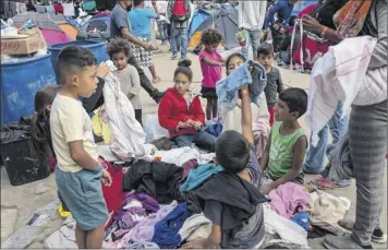  ?? Rodrigo Abd / Associated Press ?? Central American migrant children look through a pile of donated clothes on Saturday at the Benito Juarez Sports Center, which is serving as a temporary shelter, in Tijuana, Mexico.