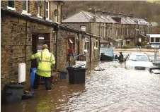  ?? — AFP photo ?? A man enters a house on a flooded street in Mytholmroy­d, northern England, after the River Calder burst its banks.
