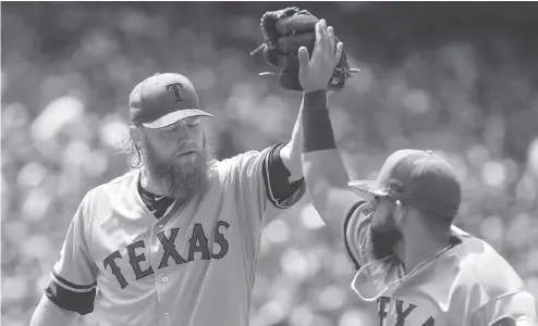  ?? CHRIS YOUNG / THE CANADIAN PRESS ?? Texas pitcher Andrew Cashner high-fives second baseman Rougned Odor during Sunday’s game at Rogers Centre in Toronto. Cashner pitched five-hit ball over seven innings as the Rangers salvaged the third game of the series with a 3-1 win Sunday.