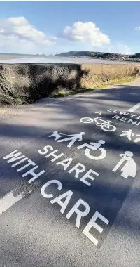  ??  ?? A ‘Share with Care’ sign painted on the seafront path at West Cross.