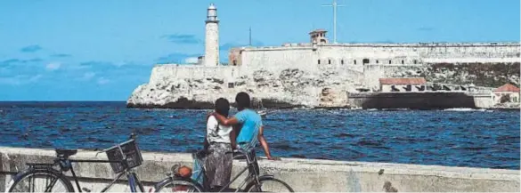  ??  ?? Dos jóvenes contemplan, desde el Malecón, el Morro y su magnífico faro, del siglo XVIII, que aún hoy dirige la navegación de los barcos hacia el puerto.