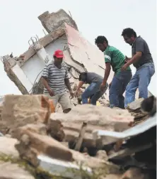  ?? Ronaldo Schemidt / AFP / Getty Images ?? Volunteers remove rubble after city hall partially collapsed in Juchitan. At least 60 people has been reported dead.