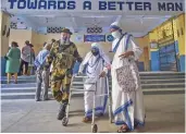  ?? — PTI ?? A Central paramilita­ry forces’ jawan helps a nun of the Missionari­es of Charity to cast her vote at a polling centre in Kolkata on Thursday.