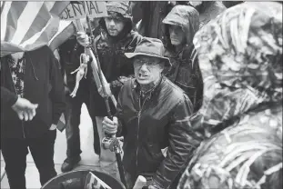  ?? Associated Press photo ?? A man with a flag on a fishing rod that had a doll with a noose around its neck attached to it grimaces as he comes to the front of the stage during a protest against the state’s stay-at-home order at the Michigan Capitol in Lansing, Mich., Thursday.