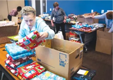  ?? STAFF FILE PHOTO BY DOUG STRICKLAND ?? Anita Stewart, left, and other BlueCross BlueShield employees sort gift-wrapped pajamas for children in their offices in 2016 in Chattanoog­a. Forbes magazine announced Thursday the company ranks No. 30 among top employers for women.