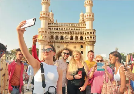  ?? — P. SURENDRA ?? A group of tourists from the United Kingdom take selfies outside the world famous Charminar though the state government has closed down all public places in the wake of the Covid-19 pandemic.