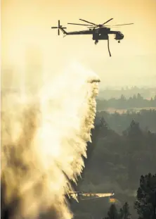  ?? Peter DaSilva / Special to The Chronicle ?? A helicopter drops water east of Sonoma. Drone no-fly zones were instituted last week around Santa Rosa and Sonoma.