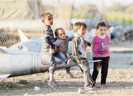  ??  ?? Syrian children play as they sit on the tip of an abandoned missile at the Ash’ari camp for the displaced in the opposition-held eastern Ghouta outside Damascus. (AFP)