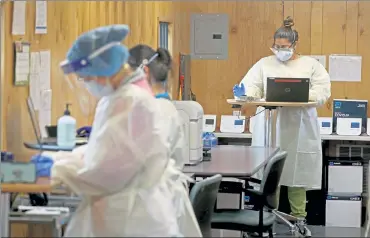  ?? MATT STONE / BOSTON HERALD ?? Workers at a makeshift COVID-19 lab at the Family Health Center on Monday in Worcester