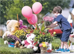  ?? DAVID ZALUBOWSKI/ASSOCIATED PRESS ?? An unidentifi­ed young boy places a bouquet of flowers Thursday on a pile of tributes outside the home where a pregnant woman and her two daughters lived in Frederick, Colo. The woman’s husband has been arrested in the disappeara­nce of the woman and children. The bodies of two young girls were submerged in crude oil for four days before authoritie­s discovered them on Thursday.